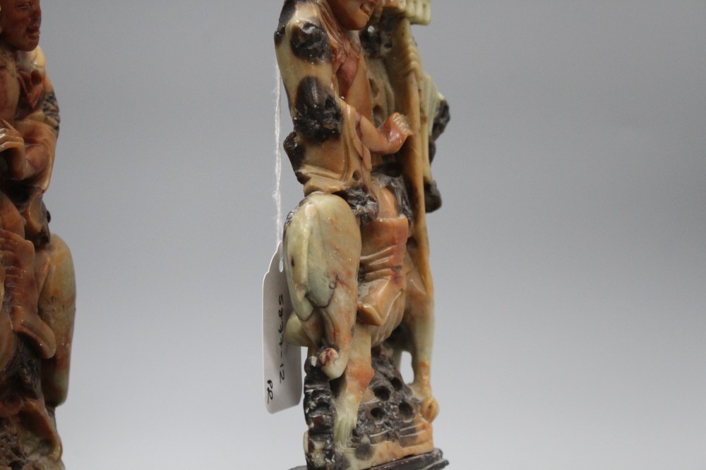 A pair of Chinese soapstone carvings depicting figures riding upon elephants, height 19cm, height with bases 27cm
